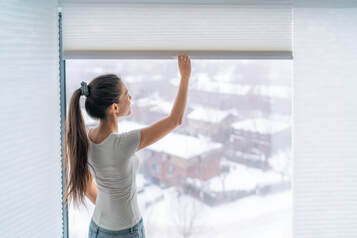 woman opening cellular shades