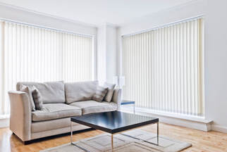 couch and table in a room with large windows covered by vertical window blinds