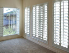 carpeted room with large windows covered by plantation shutters