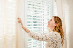 woman opening window blinds